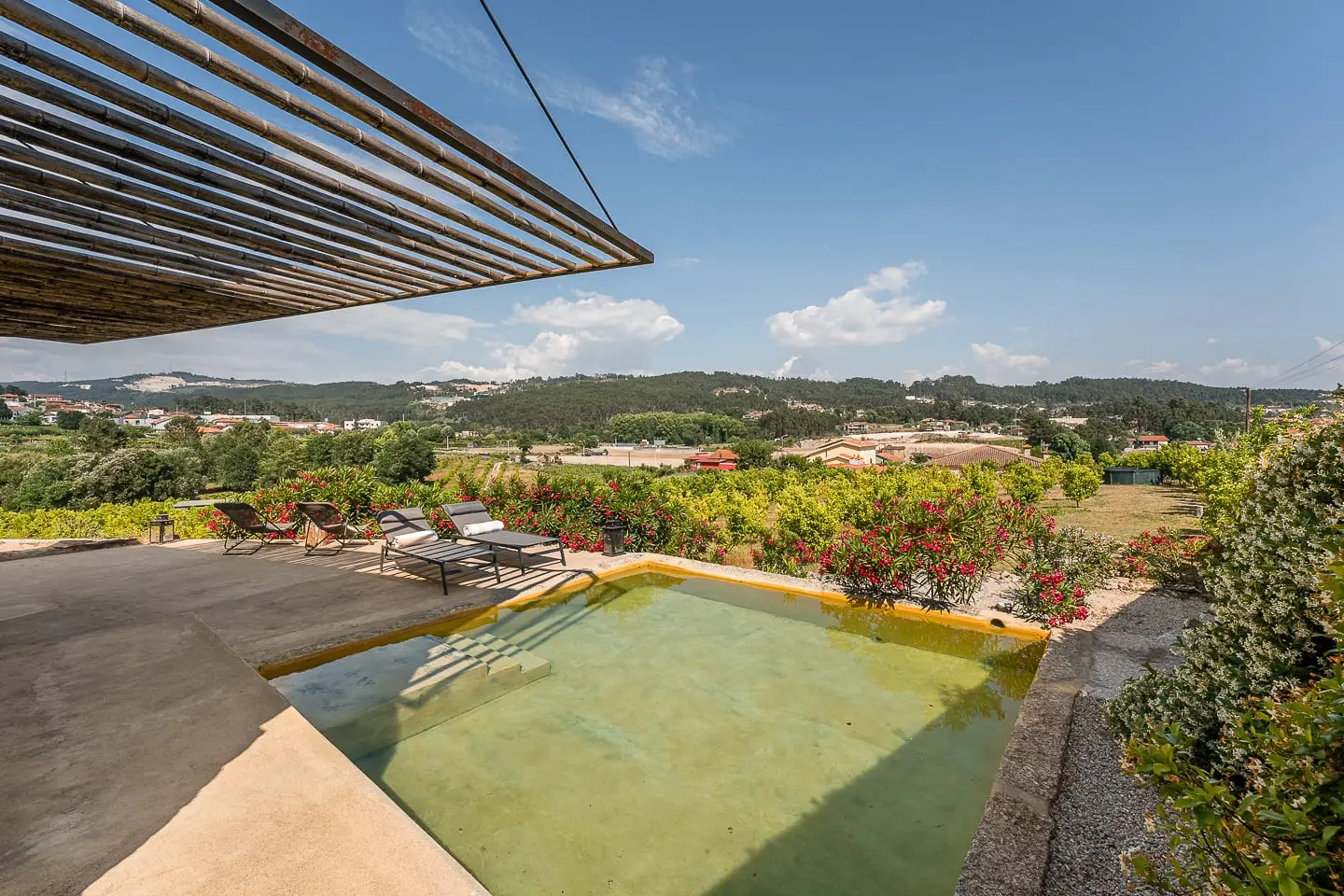 Sunlit stone terrace, flowers and pool at Casa dos Limões